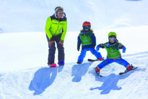 Niñera que enseña a los niños a esquiar 